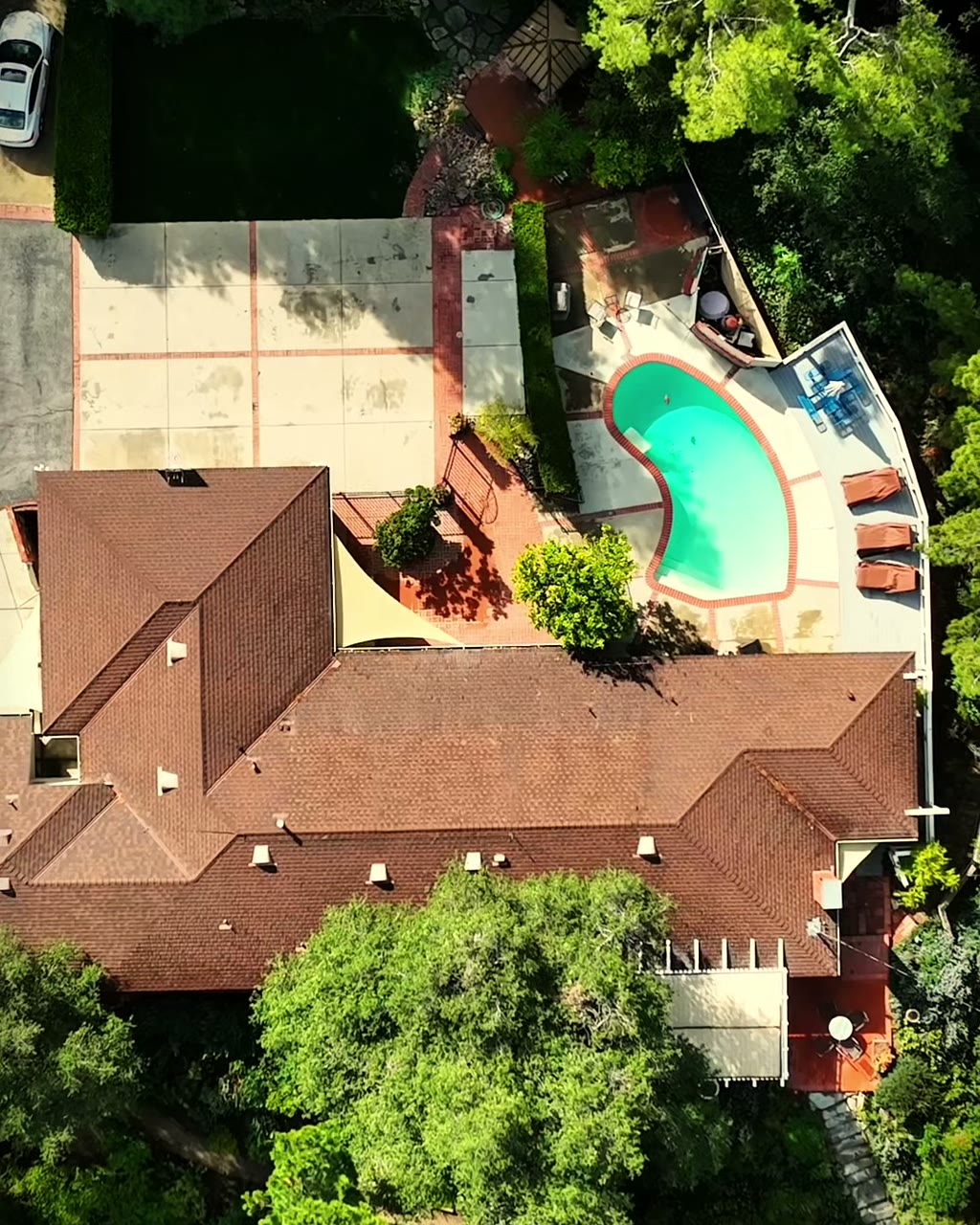 Aerial view of a hillside home with a pool and mature trees in Newhall, California